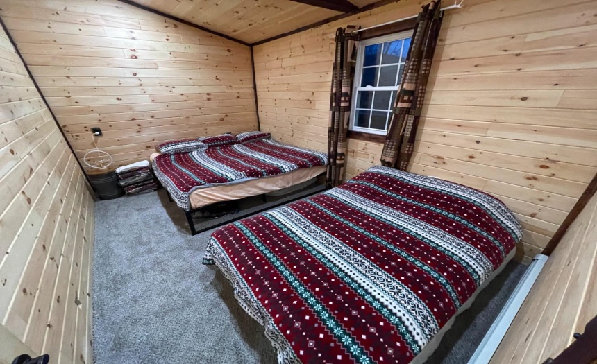 Large bedroom with carpet, open beam ceiling design & log walls