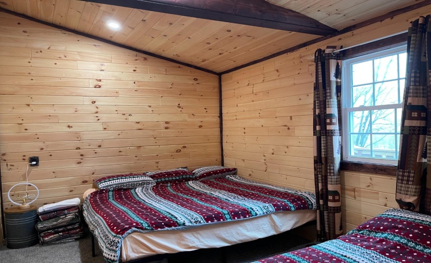 Large bedroom with carpet, open beam ceiling design & log walls