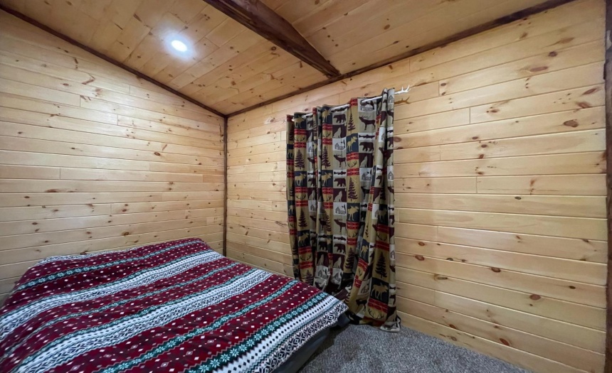 Bedroom with carpet, open beam ceiling design & log walls