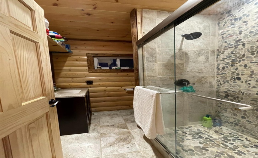 Very nice bathroom with tile flooring & log walls, and stone/rock & tile walls in shower