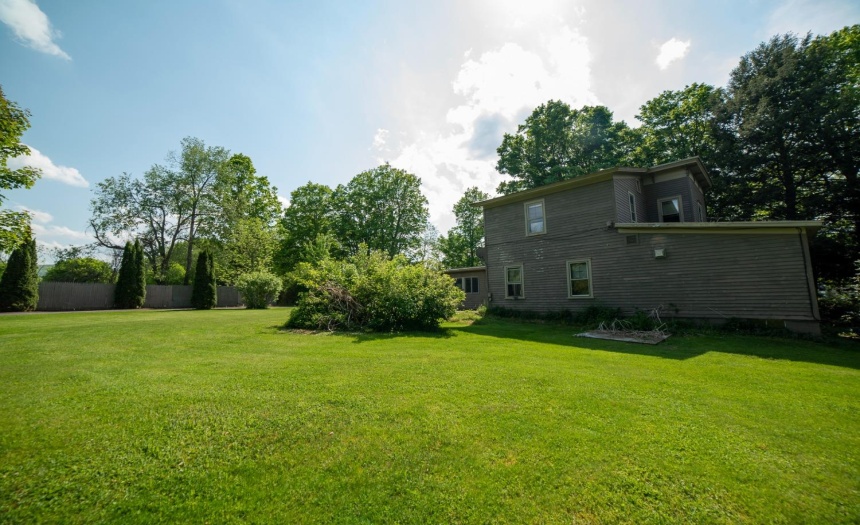 Looking over the lawn from the driveway at the side of the house.  Fence in the left foreground hides the pool.