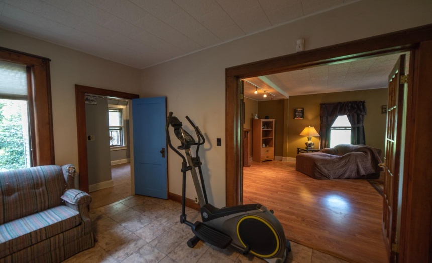 small room to the left is currently being used as a bedroom.  French doors are opened to reveal one end of the formal dining room.