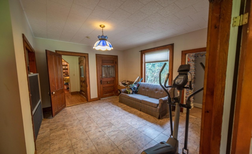 A look at the den from the living room.  Picture windows overlooks the front yard, open door to the left leads into the hall and the closed door goes out on to the porch.