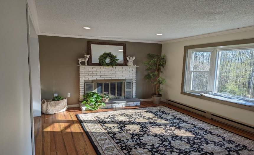 Large living room with fireplace, bay window. Nice airy space with neutral colors