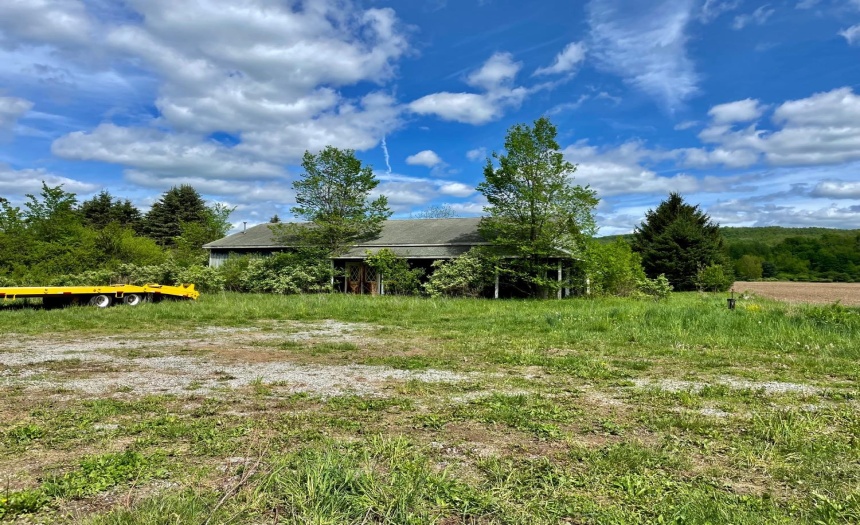 Front of building with gravel lot. Needs clearing, but salvageable.