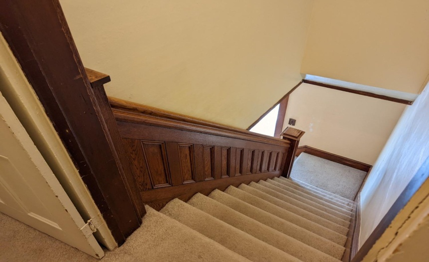 More original wood work adds beauty to stair case leading upstairs.